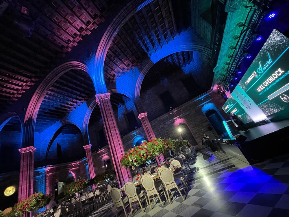 Cena de gala en salón con arcos iluminados en azul y rosa
